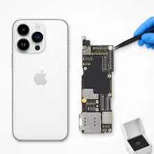 Placa base del iPhone 14 Pro Max junto al móvil, con pinzas y chip nuevo: reparar placa base del iPhone 14 Pro Max en Madrid