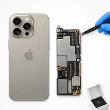 Placa base del iPhone 15 Pro Max junto al móvil, con pinzas y chip nuevo: reparar placa base del iPhone 15 Pro Max en Madrid